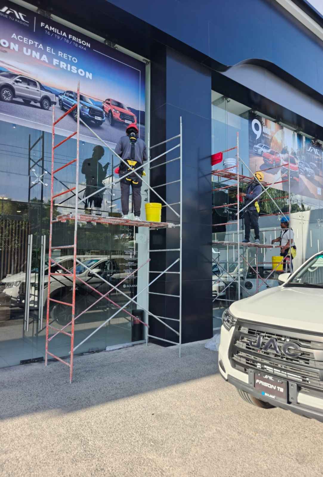 Técnico de limpieza suspendido realizando mantenimiento en fachada acristalada